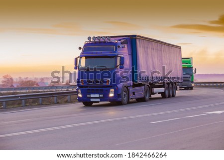 Trucks Moving On Country Road At Sunset