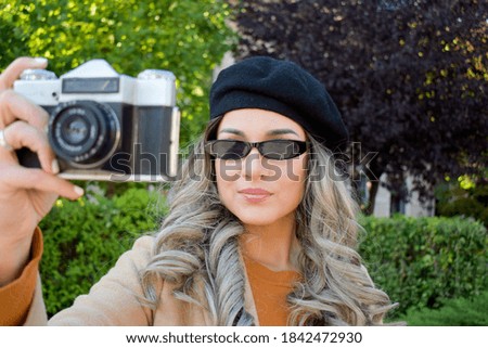 Woman with black beret hat, taking pictures, outdoors