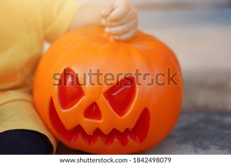 Boy sitting with scary face pumpkin on Halloween holiday. Trick or treat.
