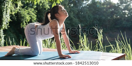Little cute girl practicing yoga pose exercise healthy in sportive top and leggings practicing yoga at nature in the park. Beautiful girl practice Cat and cow pose. female happiness.