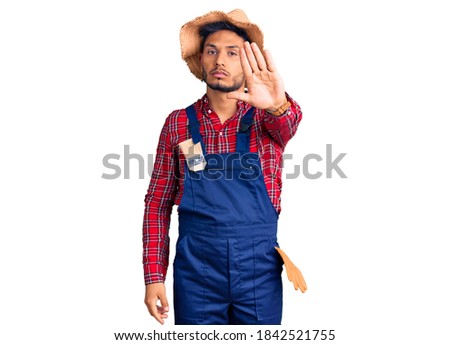 Handsome latin american young man weaing handyman uniform doing stop sing with palm of the hand. warning expression with negative and serious gesture on the face. 