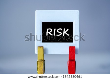 Plastic frame with clothes pin on table. White frame with black background and inscription word RISK. Business risk concept