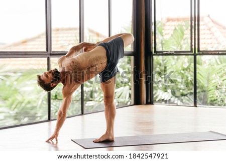Yoga men workout in studio, training in front of a window