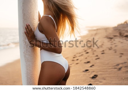 Beautiful surfer woman on the beach at sunset. Bali Indonesia.