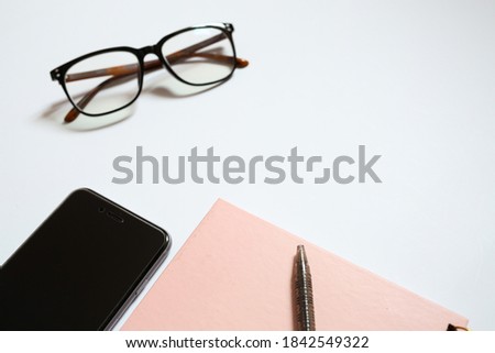 Business concept. Top view of magnifying glass, pen, notebook, glasses and smartphone isolated on a white background