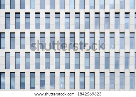 Building facade made of white natural stone with panoramic windows. Element of architecture. Detailed pictures of exterior urban architecture. Minimal modern geometric architecture shape.