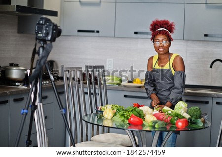 African american woman filming her blog broadcast about healthy food at home kitchen. She cuts the cabbage.