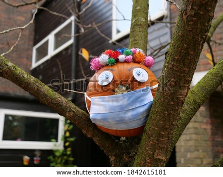 Halloween pumpkin in a protective medical face mask  and decoration on the tree. New normal concept.
