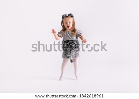 Happy little funny emotional child girl in cute Christmas wolf costume on white colored background.