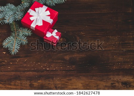 Christmas background with gifts in red boxes and branches of natural new year's blue, green Christmas tree, Kopi space. Brown beautiful textured wood surface with space for text.