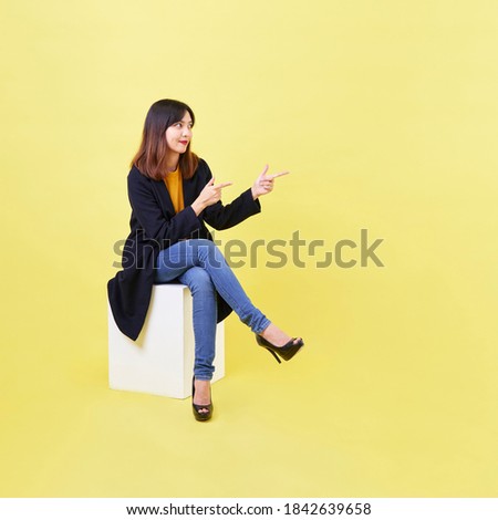 attractive young Asian woman sitting on the blank empty box on yellow background For job hunting ideas