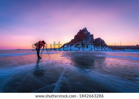 Photographer or Traveller using a professional DSLR camera take photo beautiful landscape of Baikal lake at sunset winter. The most famous tourist attraction in Rusia - Recreation and outdoor travel c