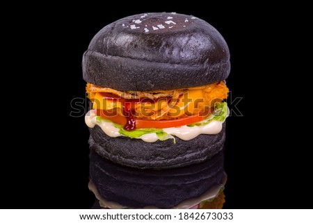 Tasty black chicken with lettuce, tomato, and sauce, isolated on black background