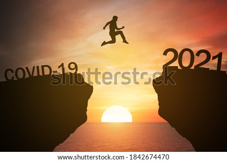 silhouette man jump from the mountain from 2020 which covid-19 spread to 2021 years with the sunset or sunrise background. Happy and success growth with new year 2021 concept Royalty-Free Stock Photo #1842674470