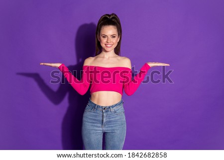 Photo of cheerful pretty lady two palms hold empty space wear cropped pink top isolated purple color background