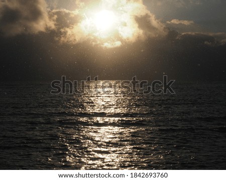 Dramatic winter sky with clouds during sunset with sunlight over ocean