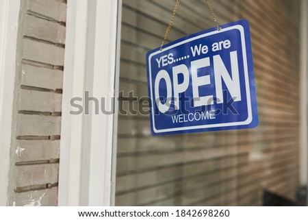 A weighty blue sign on the glass door of the clothing store - (open). Concept of covid-19