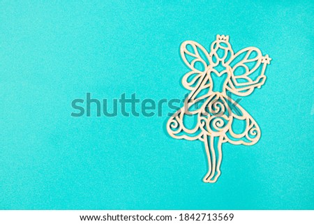 The figure silhouette of the fairy angel on the blue background of the flat lay. Christmas opening in a minimalist style with a place for text.
