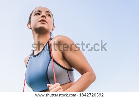 Isolated cropped shot of 20s beautiful white female athlete with elastic band wearing sporty top