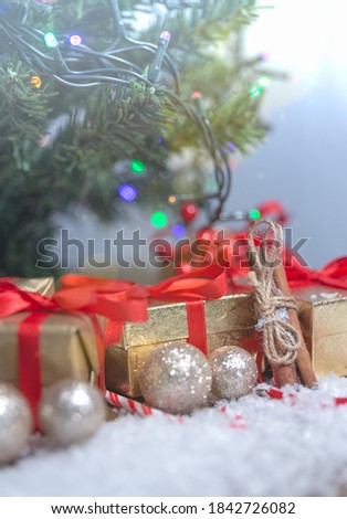balls and gifts with red ribbons under the Christmas tree in close-up