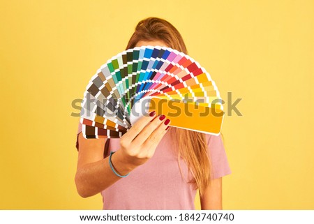 interior designer woman holding a color guide palette isolated on yellow background