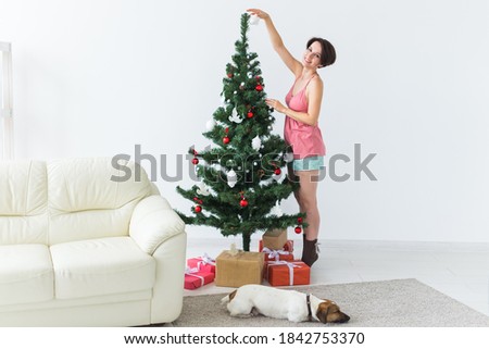 Beautiful young woman decorating a Christmas tree. Holidays and celebrations concept.