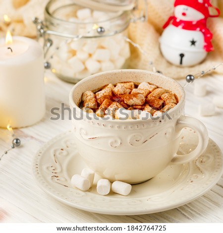Coffee, cocoa, hot chocolate with marshmallows and cinnamon in a white Cup on a wooden table. New year. The concept of comfort and relaxation with candles, spices and Christmas toys. Square picture