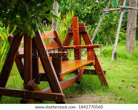 Classic outdoor garden wooden chairs hanging on frame porch swing bench furniture in the garden
