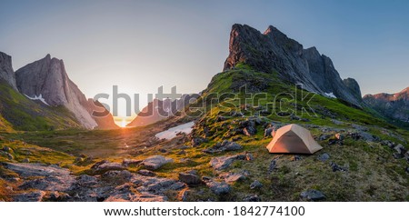 wild camping in the lofoten islands. camping tent among mountains. sunset over camping spot behind polar circle. Panorama of perfect landscape during midnight sun Royalty-Free Stock Photo #1842774100