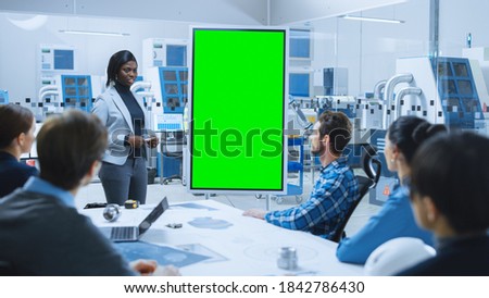 On Meeting Chief Industrial Engineer Reports to a Group of Specialists, Managers, Uses Digital Whiteboard with Green Screen Chroma Key Display. Professionals Finding Solution in Modern Factory Office