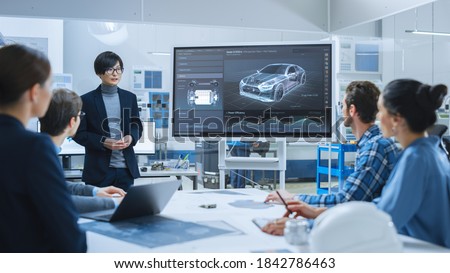 On a Meeting Asian Specialist Reports to a Group of Engineers, Managers, Presents New Electrical Car Concept, Using Digital Whiteboard. Electric Car Development, Factory.