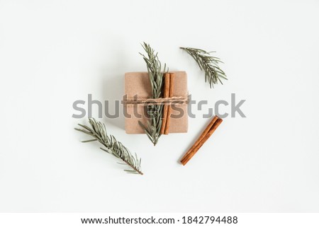 Creative flat lay of Christmas craft gift box on the white background. Hand made brown box with Christmas tree branch and cinnamon sticks. Christmas composition.