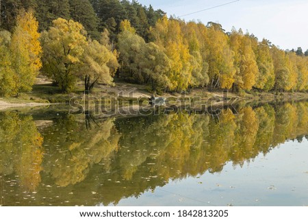 Beautiful autumn forest landscape with a lake. Autumn trees are reflected in the lake.
