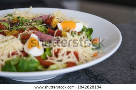 Mixed organic salad plate with tomatoes, eggs, ham and croutons, product picture