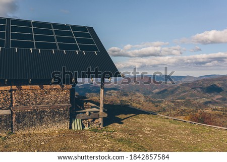 photo of a house in the mountains, on the roof of a solar panel, sunset