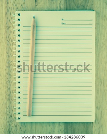 note pad with pencil on wooden background vintage style.