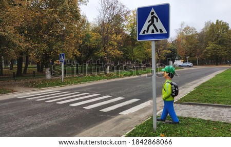 Pedestrian crossing with appropriate road signs and figure-dummy in the form of schoolboy with a backpack, on which is written the word Attention in Ukrainian