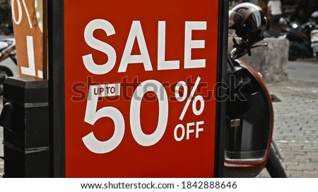 Red sign hanging on a glass window with the inscription sale up to 50% off