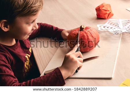 Halloween, decoration and holidays ideas- close up of kid with knife carving pumpkin or jack-o-lantern. 6 years boy has homefamily fun activity. Mom spending time with son together