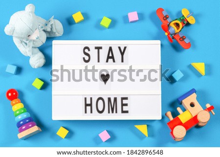Stay at home. Lightbox with text STAY HOME and baby kid toys on blue background. Coronavirus, Covid-19, quarantine and social distancing concept