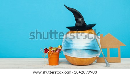 pumpkin with a medical face mask gourd, squash witch hat and bat wings. concept autumn holidays halloween and thanksgiving day during the COVID-19 pandemic