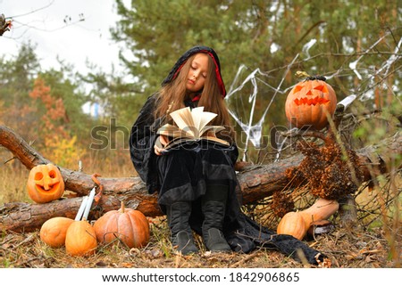 Happy Halloween.Beautiful girl witch with magic Book . little girl which celebrate Halloween outdoor and have fun. Kids trick or treating