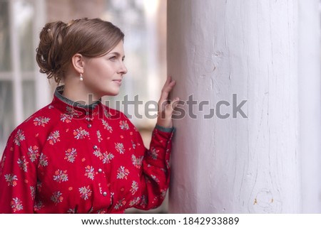 Portrait profile of face young beautiful woman in red dress who standing next to the column