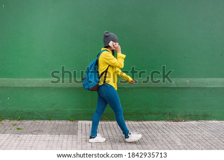 Stock photo of happy girl wearing face mask using her smartphone in the street.