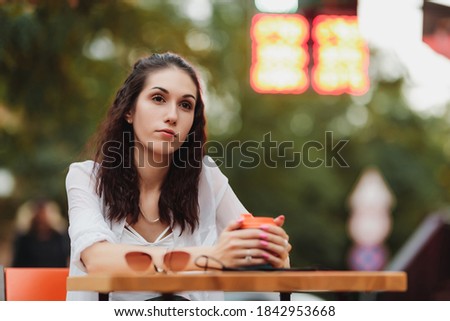 Woman sitting at a table on the street. Evening warm city. High quality photo