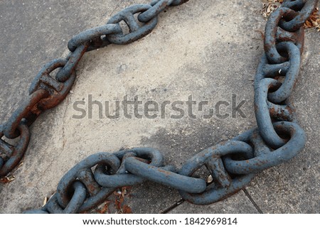 ancient heavy chain with thick links, on a ground with sand -  industrial object in a harbor