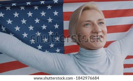 Portrait of beautiful young blond woman holding USA flag. High quality photo