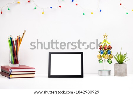 office or home workplace mockup. template christmas greeting card. white table top with blank frame on it. stationery and christmas decorations at desktop. side view.
