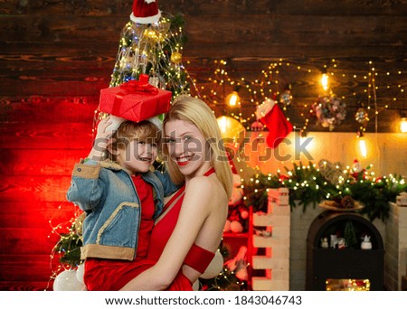 Child with a Christmas present on wooden house background. Happy child with Christmas gift