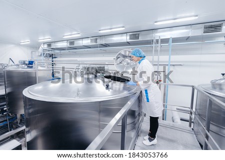 Dairy production, operator woman engineer checks temperature of steel tank with milk. Industrial worker concept. Royalty-Free Stock Photo #1843053766